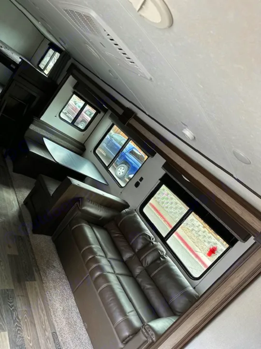 Spacious RV rental interior featuring a comfortable leather sofa, dinette, and large windows. Ideal for travel.. Keystone RV Springdale 2021