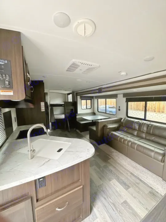 Inside this RV rental: a modern interior featuring a kitchen with a curved counter, and a comfortable sofa.. Keystone RV Springdale 2021