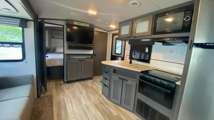 Bright RV rental interior showcasing a modern kitchen, living area with TV, and bedroom access. Your next adventure awaits!. Cruiser Rv Corp Cruiser 2021