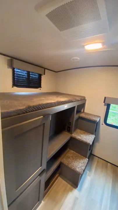 RV rental bunk bed area with dark gray mattress, built-in storage, and carpeted steps, ideal for family trips.. Cruiser Rv Corp Cruiser 2021