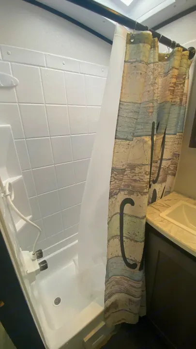 RV rental's compact bathroom: Features a clean shower stall with a decorative curtain and small sink vanity.. Cruiser Rv Corp Cruiser 2021