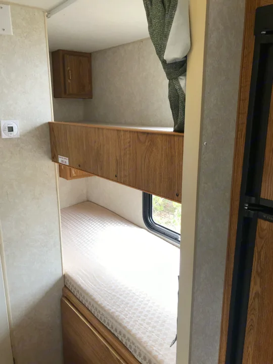 RV rental interior: sturdy bunk beds, 350 lb capacity, with a lower window, creating a compact sleeping space.. Wilderness Lite 2003