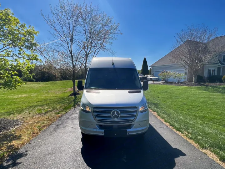 A silver Mercedes-Benz Sprinter van, ready for RV rental, parked on a sunny driveway in front of a house.. Ultimate Toys Ultimate Coach 2023