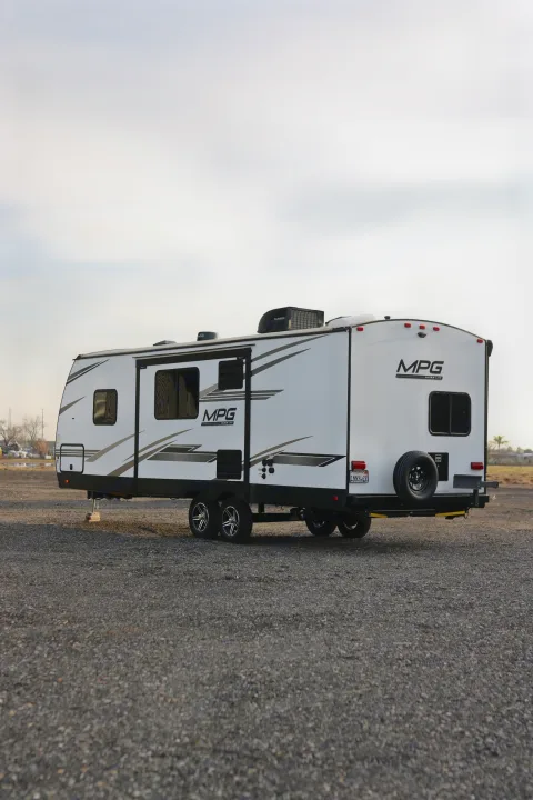 Side view of a white MPG Ultra-Lite travel trailer parked on a gravel lot, ready for rv rental.. Cruiser RV MPG Ultra Lite 2022