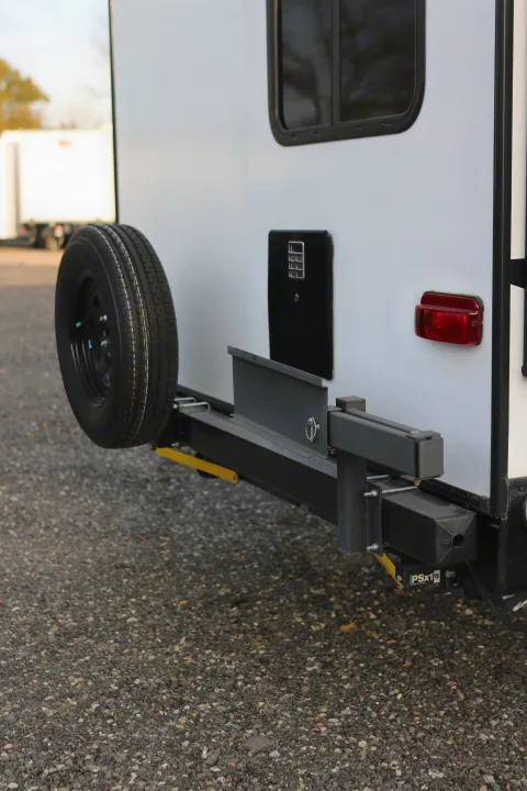 Rear view of an RV rental, showcasing a mounted spare tire and taillight, parked on a gravel lot.. Cruiser RV MPG Ultra Lite 2022