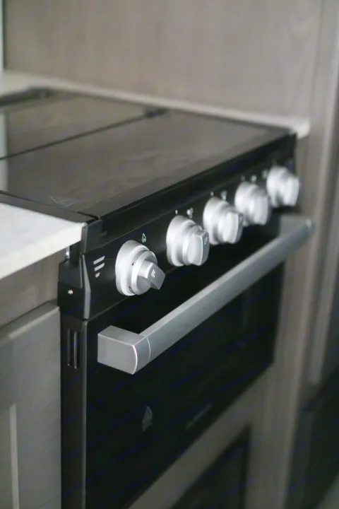 Sleek, modern oven/stove unit with silver control knobs and handle, perfect for your RV rental kitchen.. Cruiser RV MPG Ultra Lite 2022