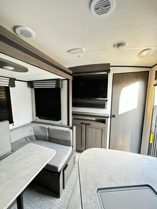 Spacious RV rental interior featuring a modern dinette, entertainment center, and comfy seating for your road trip comfort.. Cruiser RV MPG Ultra Lite 2022