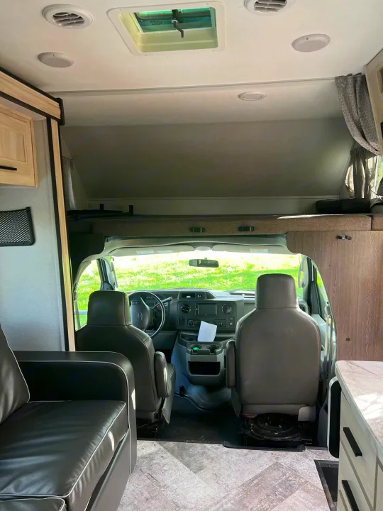 Interior view of an RV rental, featuring the driver's cab, overhead bunk, and living area.. Forest River Sunseeker Classic 2020