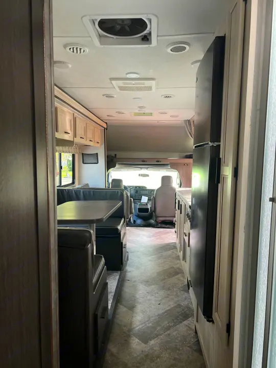 Interior view of a clean rv rental, showing the dinette, kitchen with refrigerator, and cockpit area.. Forest River Sunseeker Classic 2020