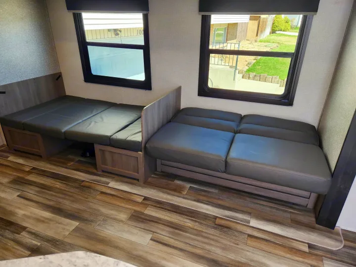 RV rental interior features versatile grey seating that converts to a bed, alongside comfortable sofa and wood-look flooring.. Starcraft Autumn Ridge 2022