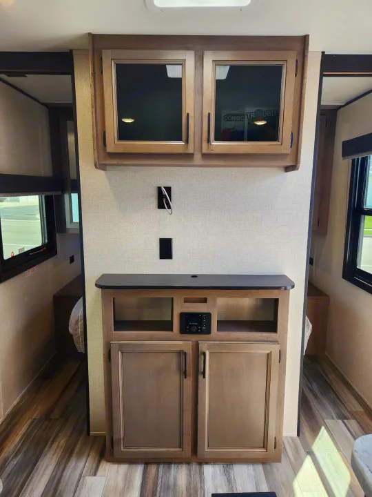 Inside an RV rental: a modern entertainment center with storage cabinets and warm wood tones. Cozy living space.. Starcraft Autumn Ridge 2022