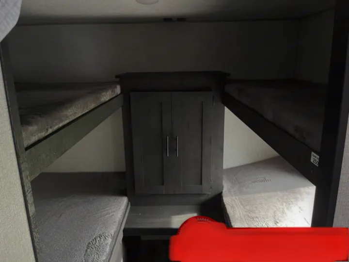 RV rental: Dark wood bunk beds with grey mattresses and a central storage unit, maximizing space in this modern interior.. K-Z Manufacturing Sportsman Classic 2022