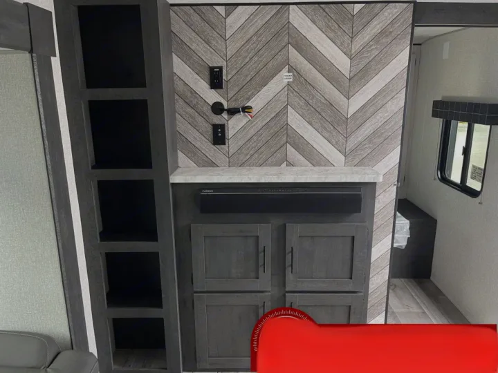 Spacious RV rental interior featuring a modern chevron accent wall, built-in entertainment center with soundbar, and sleek storage.. K-Z Manufacturing Sportsman Classic 2022