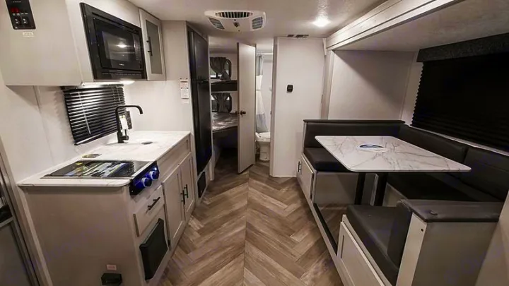 View of a modern RV rental interior featuring a bright kitchen, U-shaped dinette, and rear sleeping/bath areas.. Forest River Salem FSX 178bhsk 2023