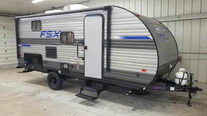 Compact grey Salem FSX travel trailer shown indoors, ready for an RV rental. Features steps, door, and front propane tank.. Forest River Salem FSX 178bhsk 2023
