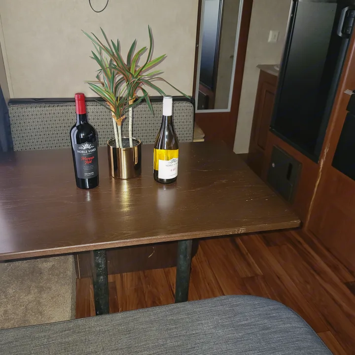 Inside an **RV rental**: a wooden table with wine bottles & a plant, beside a cozy seating area. Shows relaxing travel decor.. Forest River Salem 2016