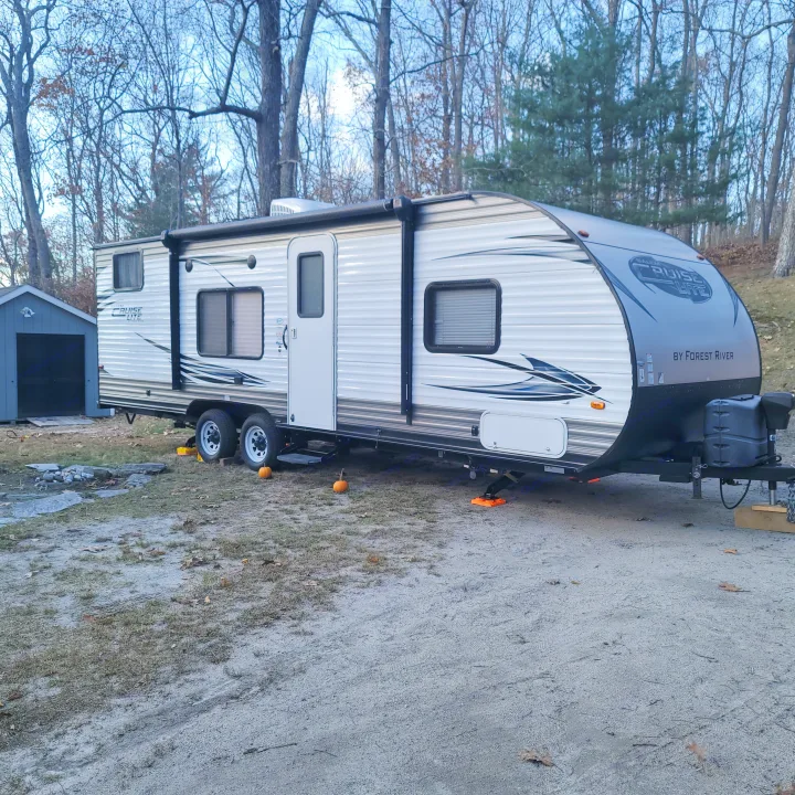 A grey and white travel trailer, branded 'Salem Cruise Lite', parked at a campsite, perfect for an RV rental getaway.. Forest River Salem 2016