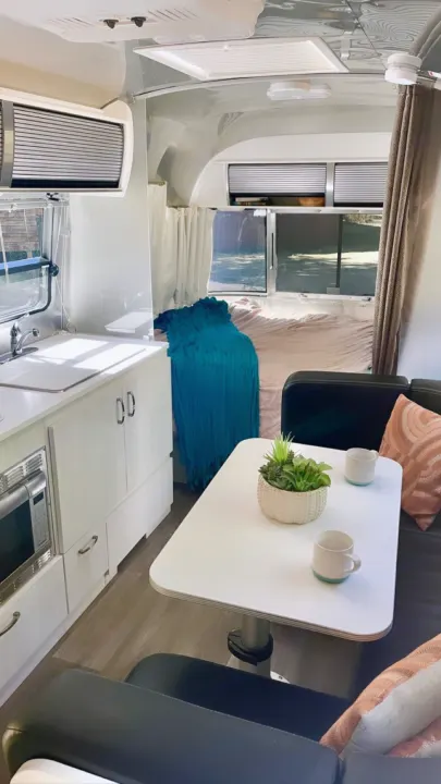 Bright RV rental showcasing a compact kitchen, dinette, and sleeping area. Enjoy mobile comfort on your trip.. Airstream Sport 2019