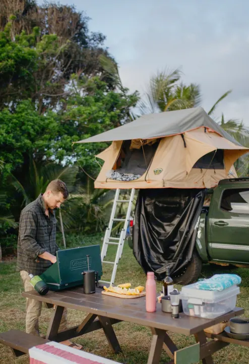 Enjoying outdoor cooking from a rooftop tent setup. Ideal for an RV rental getaway and truck camping adventures.. Toyota Tacoma 2021
