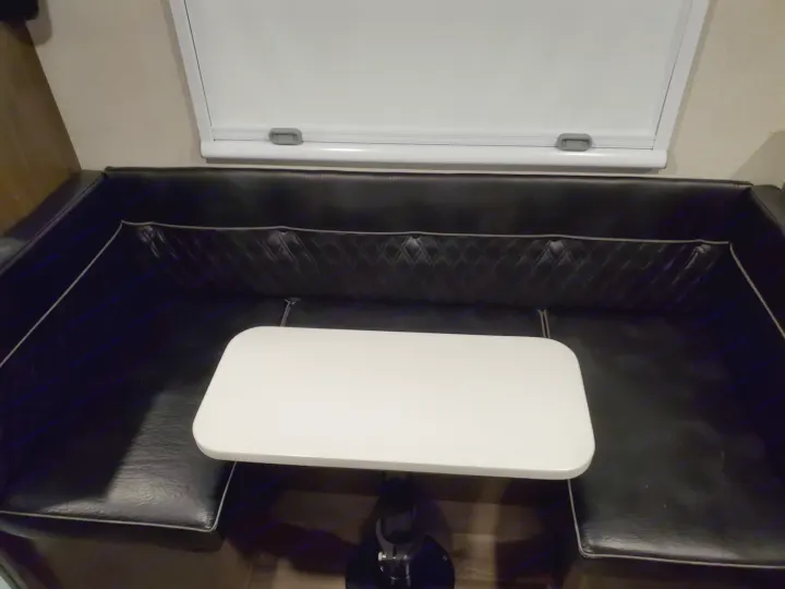 This RV rental features a practical dinette area with sleek black bench seating, a white tabletop, and a pull-down blind above.. Imperial Outdoors XploreRV 2023