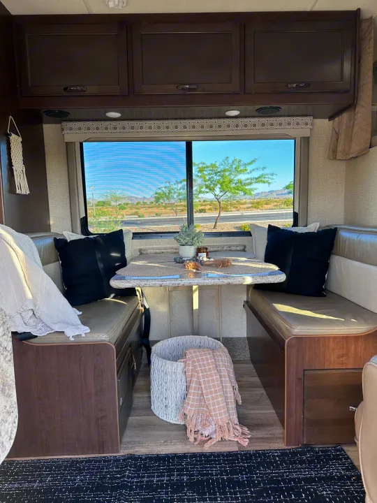 Cozy RV rental dinette with comfortable seating, a styled table, and a beautiful desert landscape view from the window.. Thor Four Winds 2020