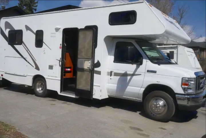 White Class C RV rental parked outdoors with its entry door open, ready for adventure.. Thor Majestic 2012