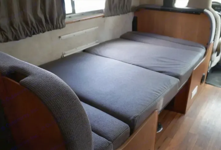 RV rental interior: a versatile bed/seating area with gray fabric cushions, wood trim, and window.. Thor Majestic 2012