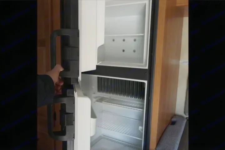 Inside an RV rental, a hand opens the clean, empty refrigerator with top freezer. Ready for your adventure.. Thor Majestic 2012