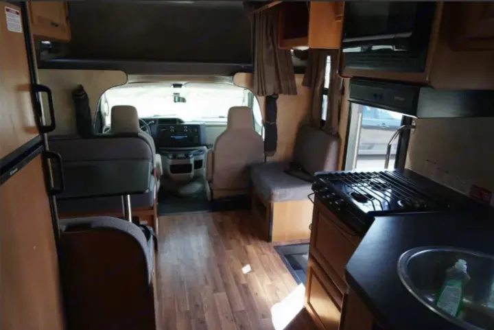This RV rental interior features a full kitchen (sink, stove, microwave), dining area, and cab for comfortable travel.. Thor Majestic 2012