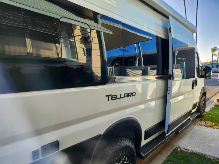 White Tellaro camper van, ideal for rv rental. Side door open, reflections of houses on windows.. Thor Tellaro 2023