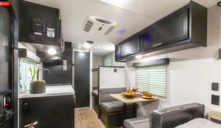 An RV rental's interior shows a modern kitchen, dining area, bunk beds, and a main bed, designed for travel comfort.. Forest River Cherokee Wolf Pup 2022