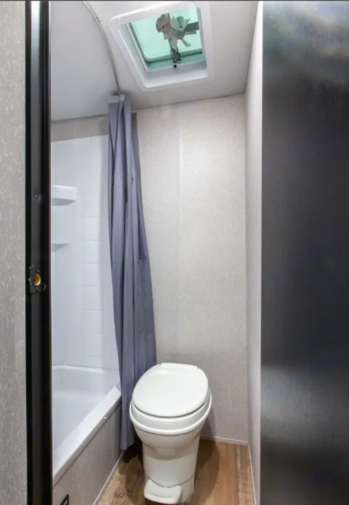 Compact RV rental bathroom features a white toilet, shower/tub, and a ceiling vent. Essential for travel comfort.. Forest River Cherokee Wolf Pup 2022