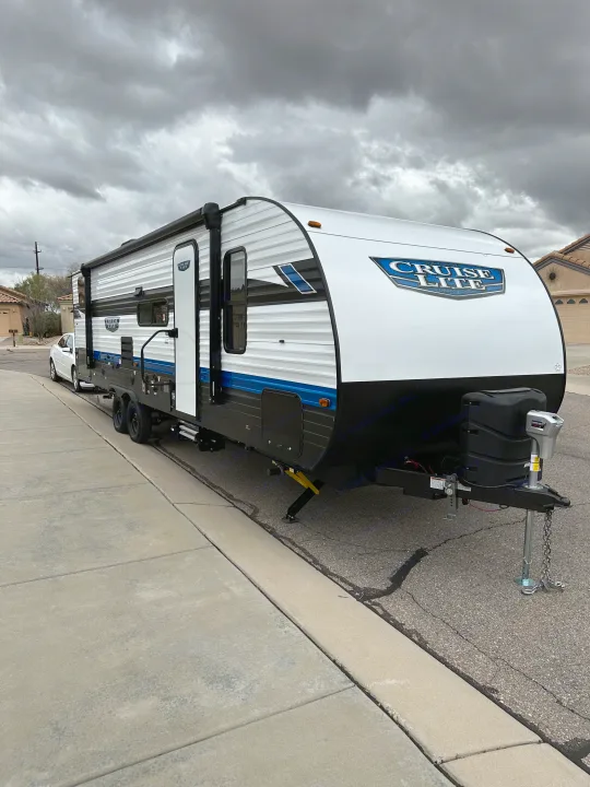 New white Cruise Lite travel trailer, an RV rental, parked on a street under a cloudy sky.. Forest River Salem Cruise Lite T282QXBL 2023
