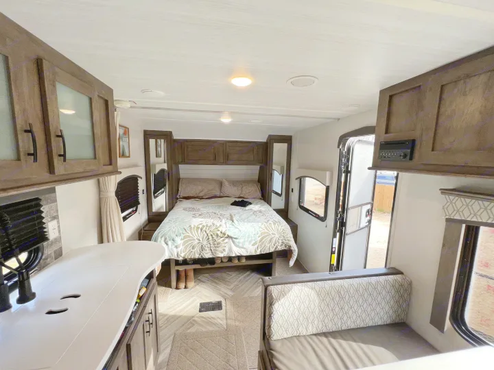 Spacious RV rental interior featuring a cozy bedroom, kitchen counter, and dinette. Ideal for travel adventures.. Forest River Evo 2020