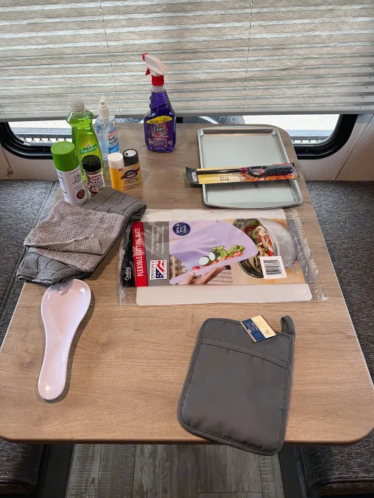 RV rental: Table full of kitchen & cleaning essentials—spray, sanitizer, spices, baking trays, cutting mats, & towels.. Forest River 16ts 2022
