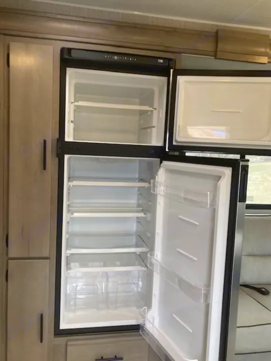 Spacious, empty refrigerator and freezer with clear shelves and door storage, perfect for your RV rental adventure.. Coachmen 26DS 2021