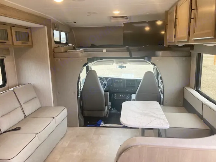 Spacious, modern RV rental interior with a comfortable dinette, sofa, and overhead bunk, perfect for travel adventures.. Coachmen 26DS 2021