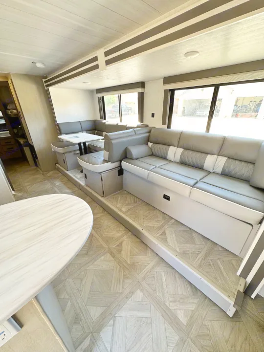 Modern RV rental interior with spacious gray sofa seating, a comfortable dinette, and stylish wood-look flooring.. Forest River Salem Cruise Lite T282QXBL 2023