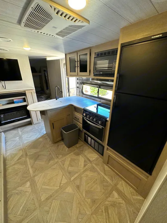 Inside a modern RV rental, featuring a bright kitchen with island, stove, Dometic fridge, and a cozy living space.. Forest River Salem Cruise Lite T282QXBL 2023