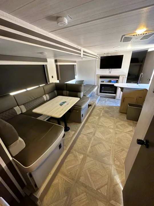 Bright and modern rv rental interior featuring a large U-shaped dinette, kitchen, TV, and fireplace. Ideal for comfortable travel.. Forest River Salem Cruise Lite T282QXBL 2023