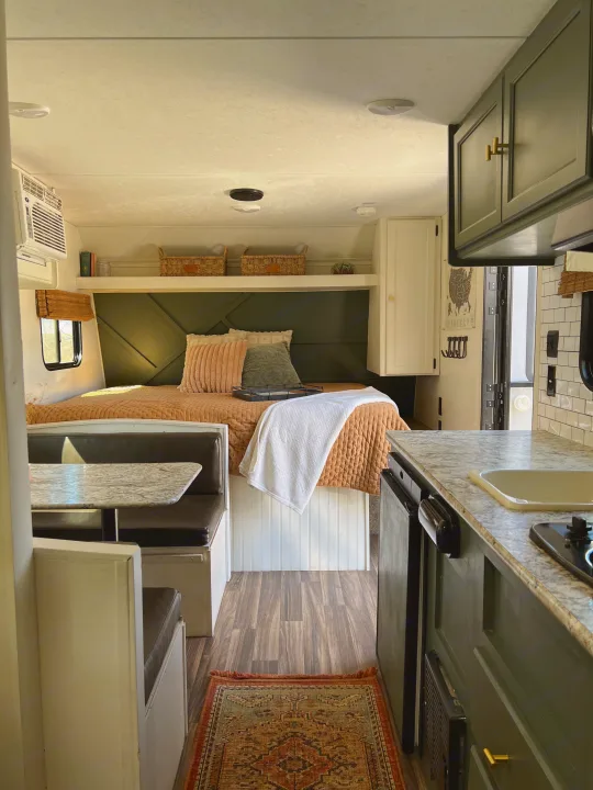 Step inside this inviting RV rental: bedroom with green accents, cozy dinette, and sleek kitchen. Your adventure awaits!. Keystone RV Hideout 2018