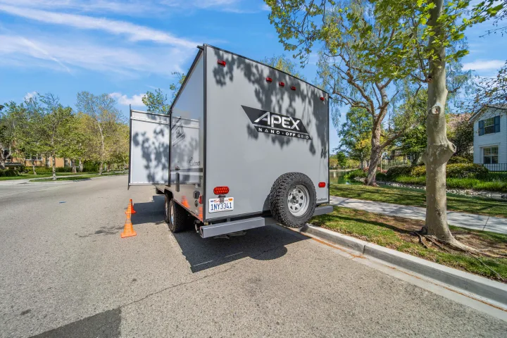 Gray Apex Nano Off Grid travel trailer rv rental, parked on a street with cones & spare tire visible.. Coachmen Apex 2022