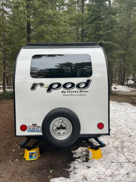Rear view of a white R-Pod travel trailer at a snowy forest campsite. A cozy rv rental option for winter camping!. Forest River R-Pod RP-190 2021