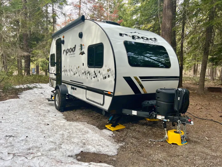 White r-pod travel trailer (RV rental) set up on a snowy campsite amidst a forest. Ready for outdoor adventures.. Forest River R-Pod RP-190 2021