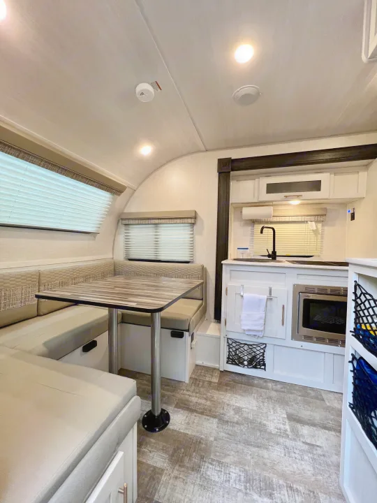 Bright RV rental interior features a cozy dinette dining area, a compact kitchen, and modern wood-look flooring.. Forest River R-Pod RP-190 2021