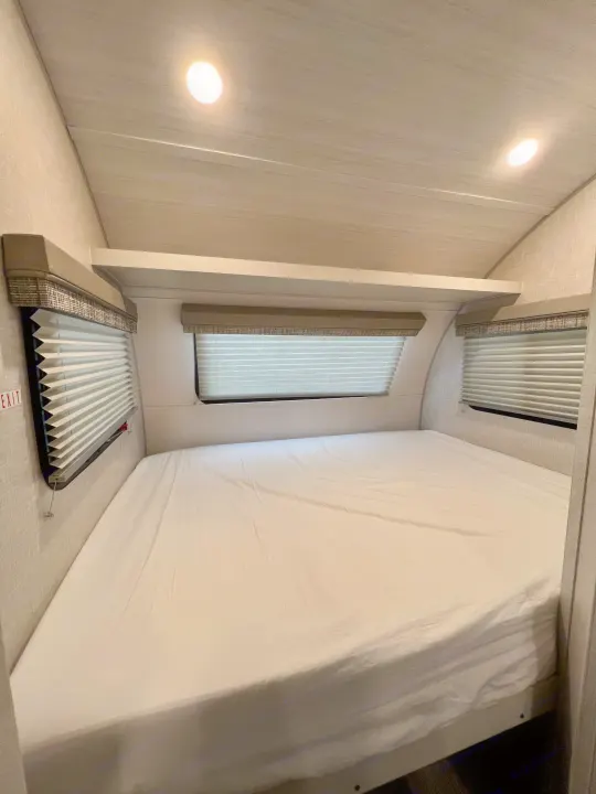 Spacious RV rental bedroom featuring a large bed, pleated window blinds, and bright overhead lighting for comfortable travel.. Forest River R-Pod RP-190 2021