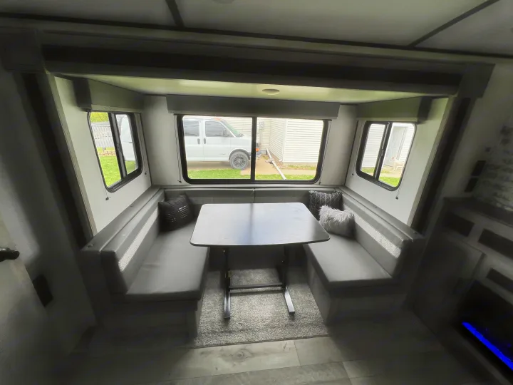 RV rental: U-shaped dinette with grey booth cushions, dark table, and expansive views through multiple windows.. Keystone Springdale 2021