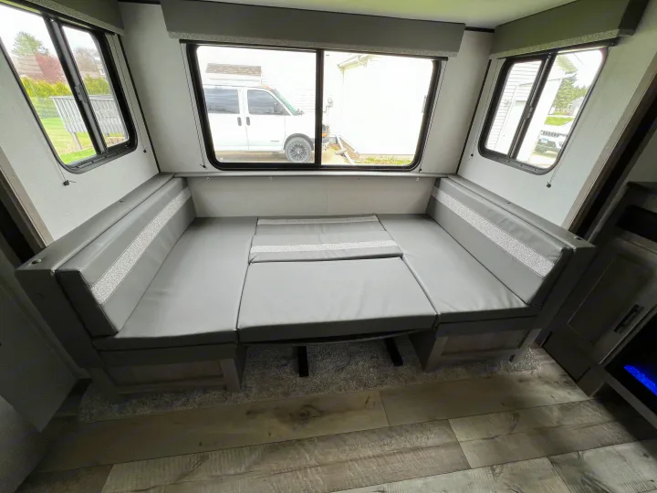 RV rental dinette seating, with gray cushions and textured accents, easily converts to a bed.. Keystone Springdale 2021
