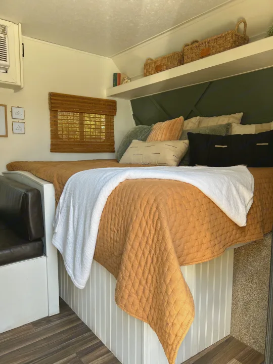 Experience comfort in this RV rental! Cozy bedroom features a quilted bed, green accent wall, and clever storage in a compact space.. Keystone RV Hideout 2018
