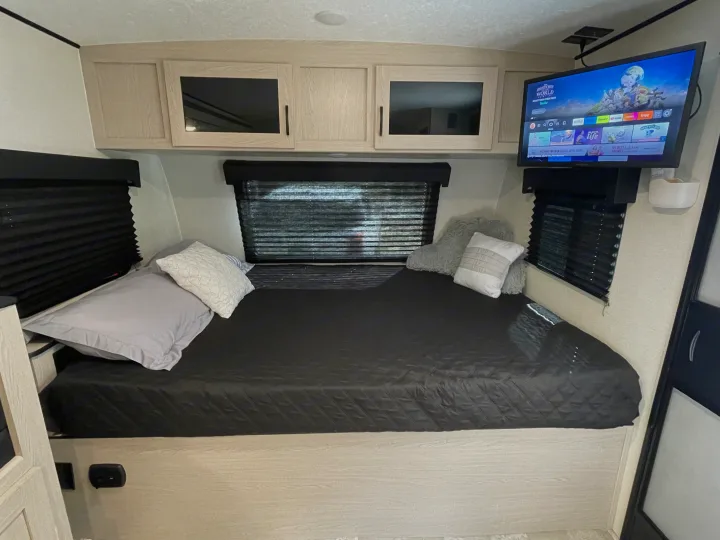 RV rental bedroom with a comfortable bed, smart TV, overhead cabinets, and window blinds for a cozy stay.. Coachmen Apex Nano 2022